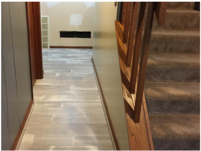 luxury vinyl hallway with carpeted stairs and wood railing